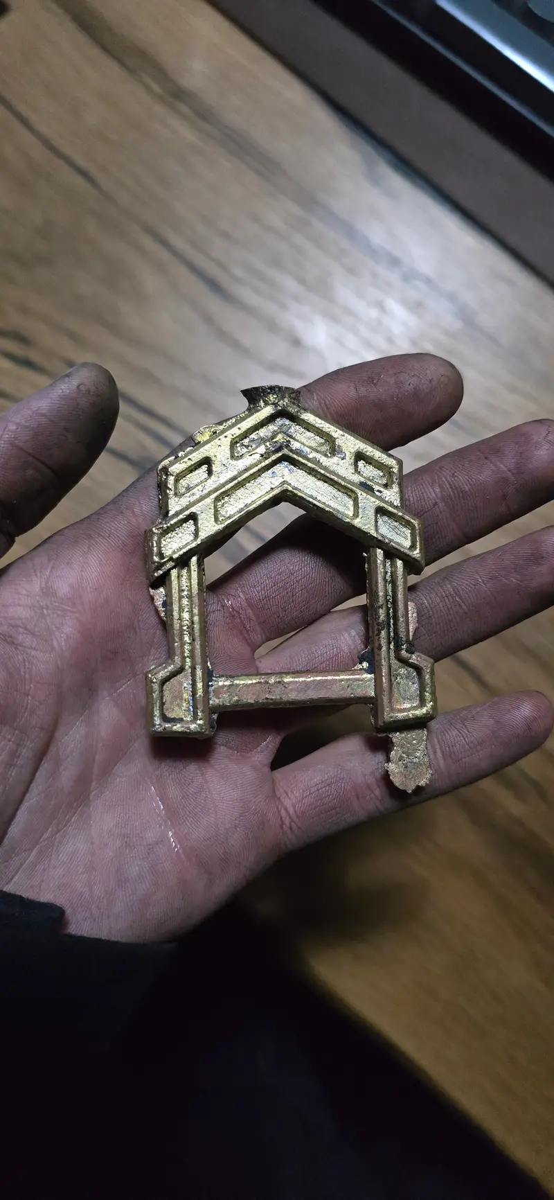 A hand holding a cast brass fitting